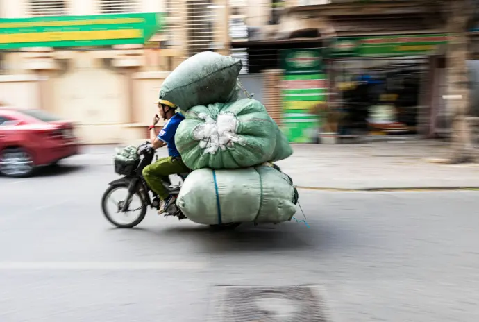A person riding a bike with a large bag on the back of it